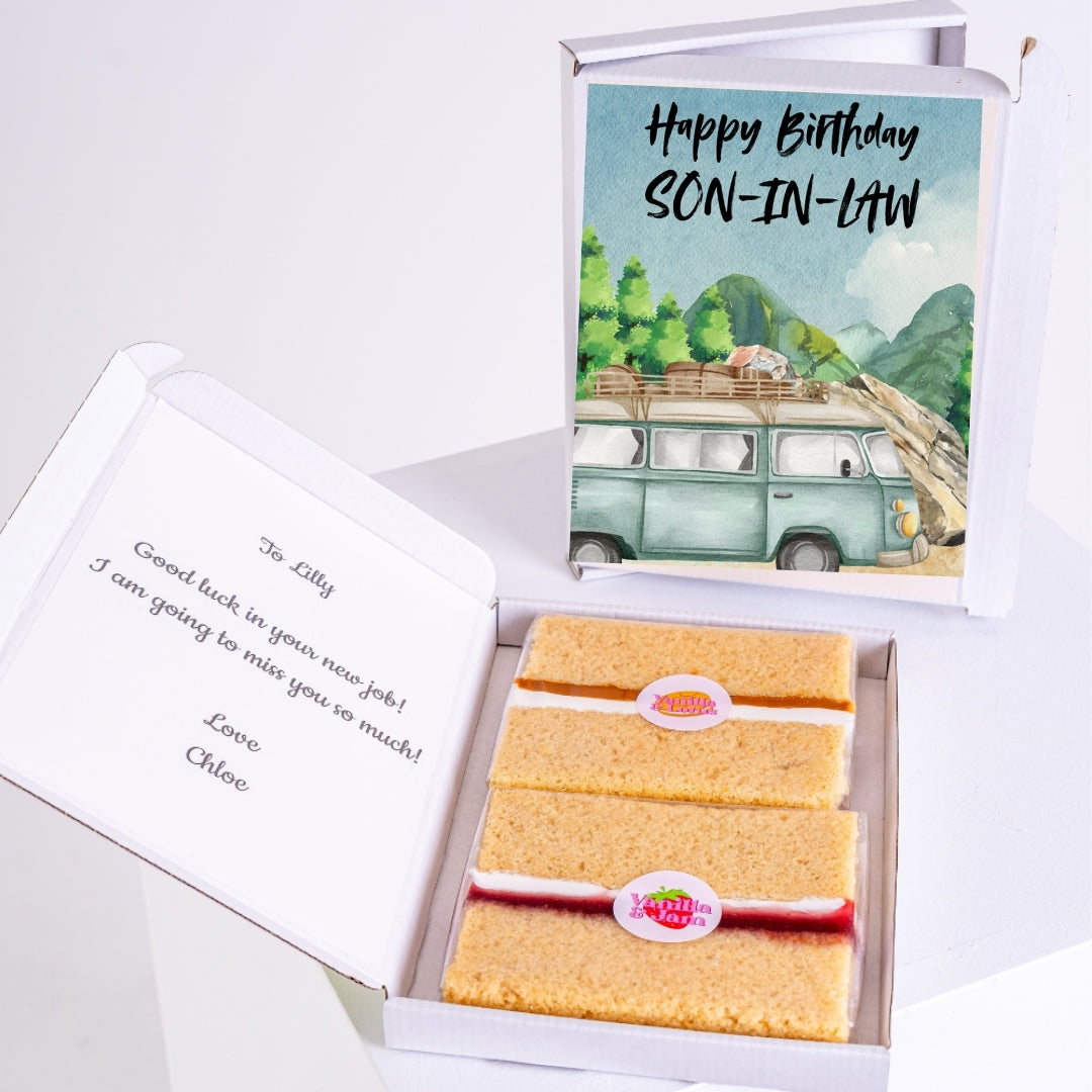 Letterbox cake gift with birthday message for son-in-law featuring a scenic mountain landscape and vintage van illustration, paired with two slices of sponge cake.