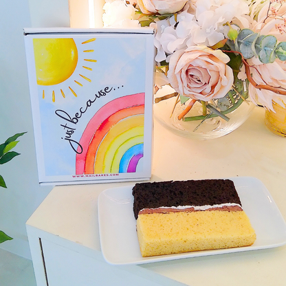 Cake slice next to just because... box with rainbow and sun.