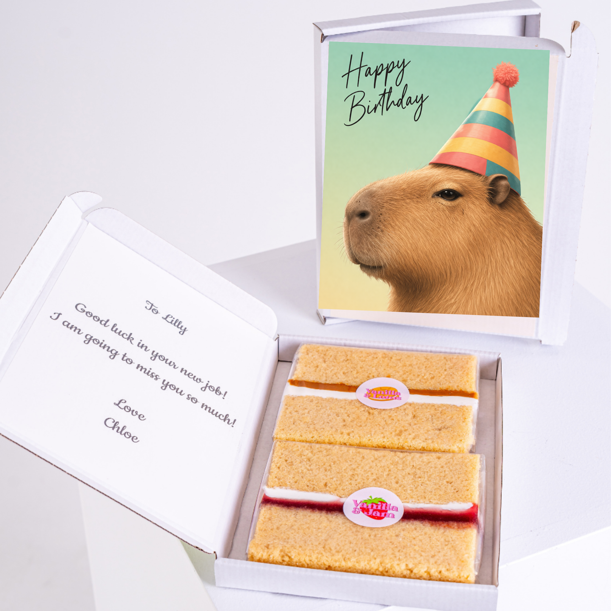 A cute capybara with a birthday hat, holding a gift, and a personalized message inside a box with two slices of cake.