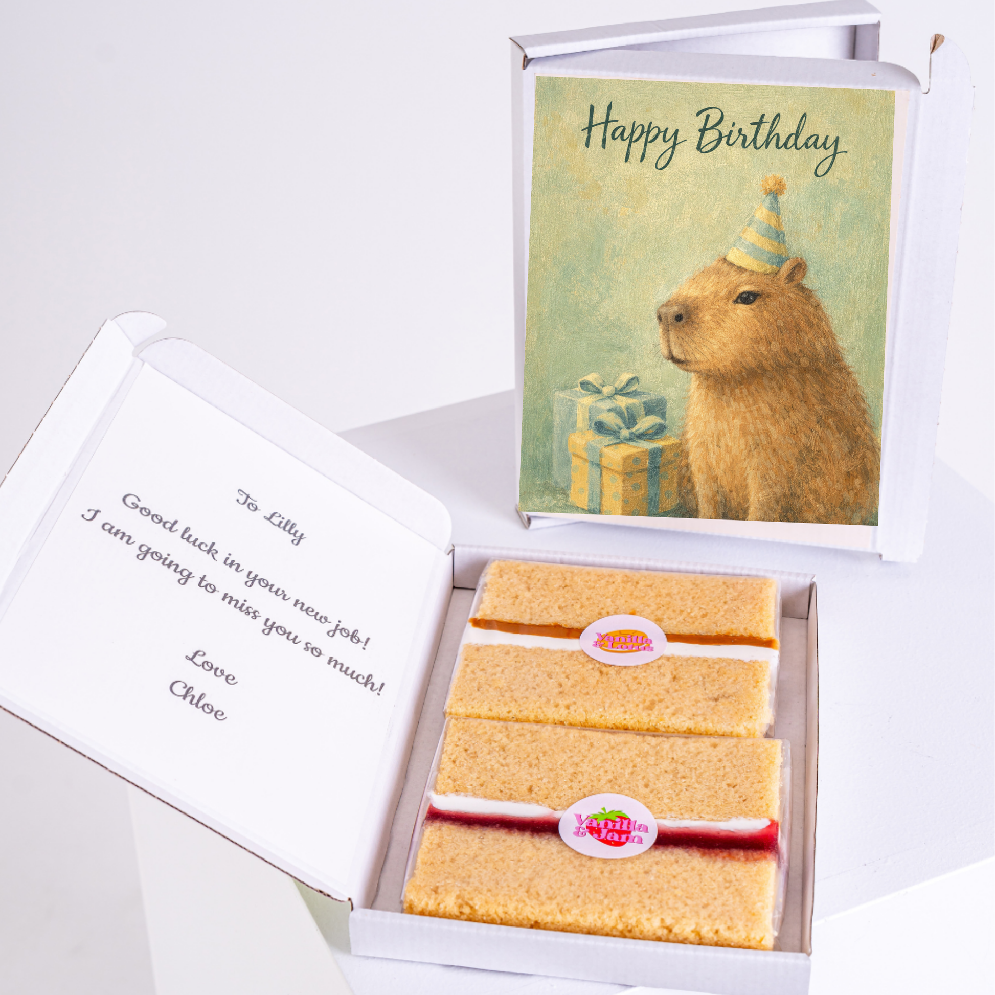 A capybara wearing a birthday hat, with a "Happy Birthday" card and two slices of cake in a box, alongside a personalized message.