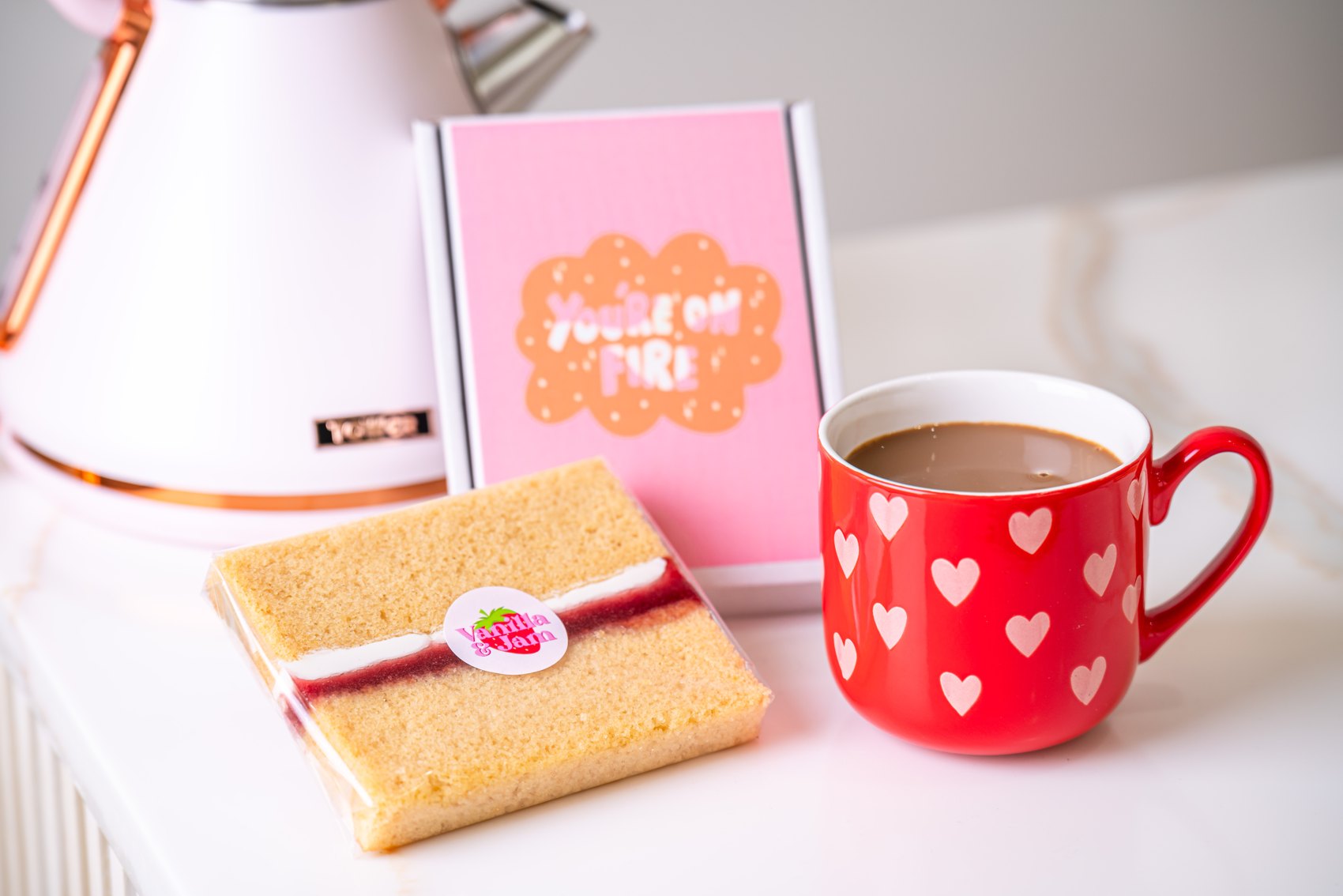 A birthday cake card and a slice beside a red mug