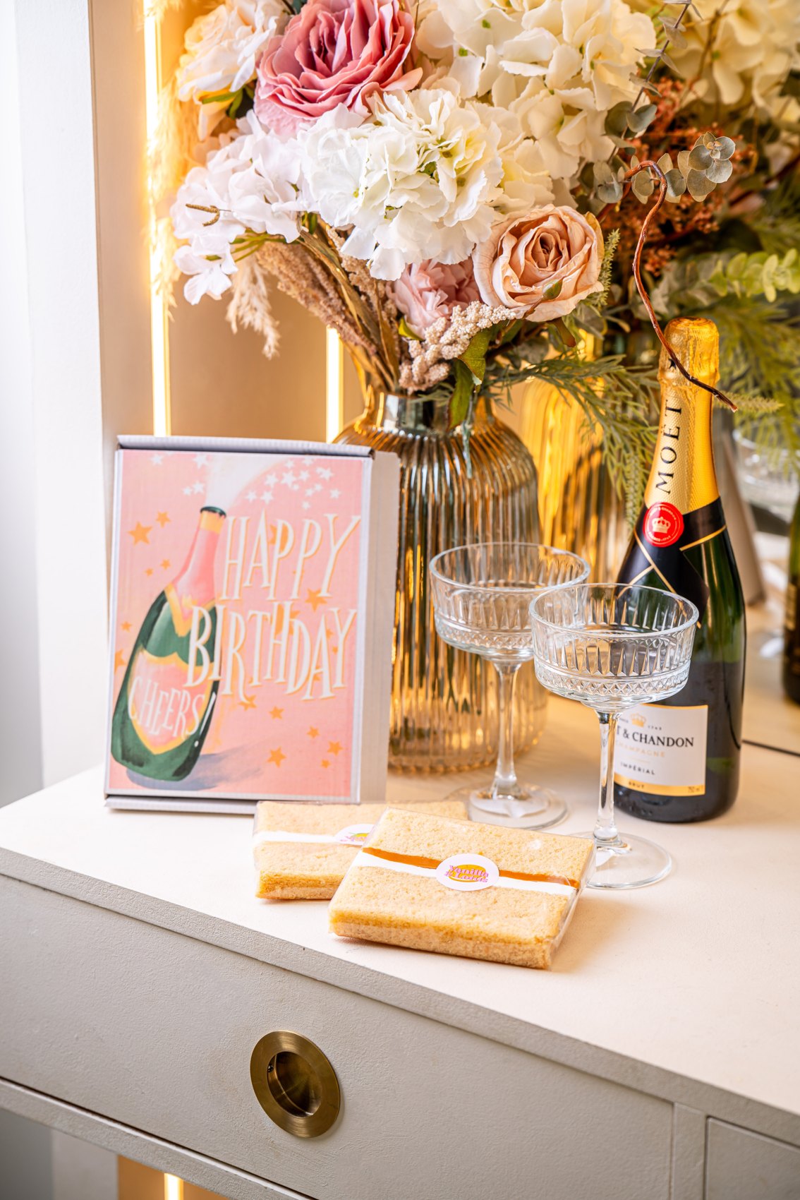 A MailBakes cake card and cake slices styled beside flowers
